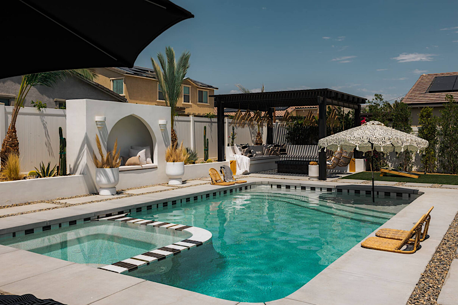 Luxurious backyard with a swimming pool, hot tub, shaded seating area, and stylish outdoor decor in Coachella Valley.