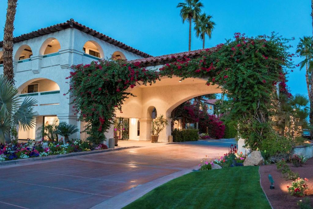 Luxurious Las Brisas Hotel in Palm Springs with Mediterranean architecture, lush gardens, and vibrant flowering plants at dusk.